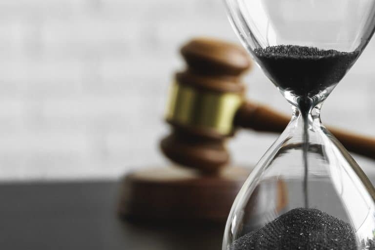 Court concept Hourglass and judge gavel on table